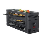 Seitliche Perspektive auf ein schwarzes Pizza-Raclette-Gerät mit mehreren Ebenen und Pfännchen, oben mit Gemüse und Garnelen dekoriert.