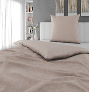 Beige Wendebettwäsche auf einem Bett, fotografiert aus einer seitlichen Perspektive mit einem Kissen im Hintergrund.