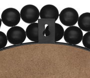 Rückansicht eines runden Spiegels mit dekorativem schwarzen Rahmen aus kreisförmigen Elementen.