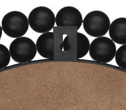 Rückansicht eines runden Spiegels mit dekorativem schwarzen Rahmen aus kreisförmigen Elementen.