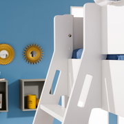 Nahaufnahme eines weißen Etagenbetts mit blauer Bettwäsche, seitliche Perspektive, im Hintergrund eine blaue Wand mit dekorativen Spiegeln.