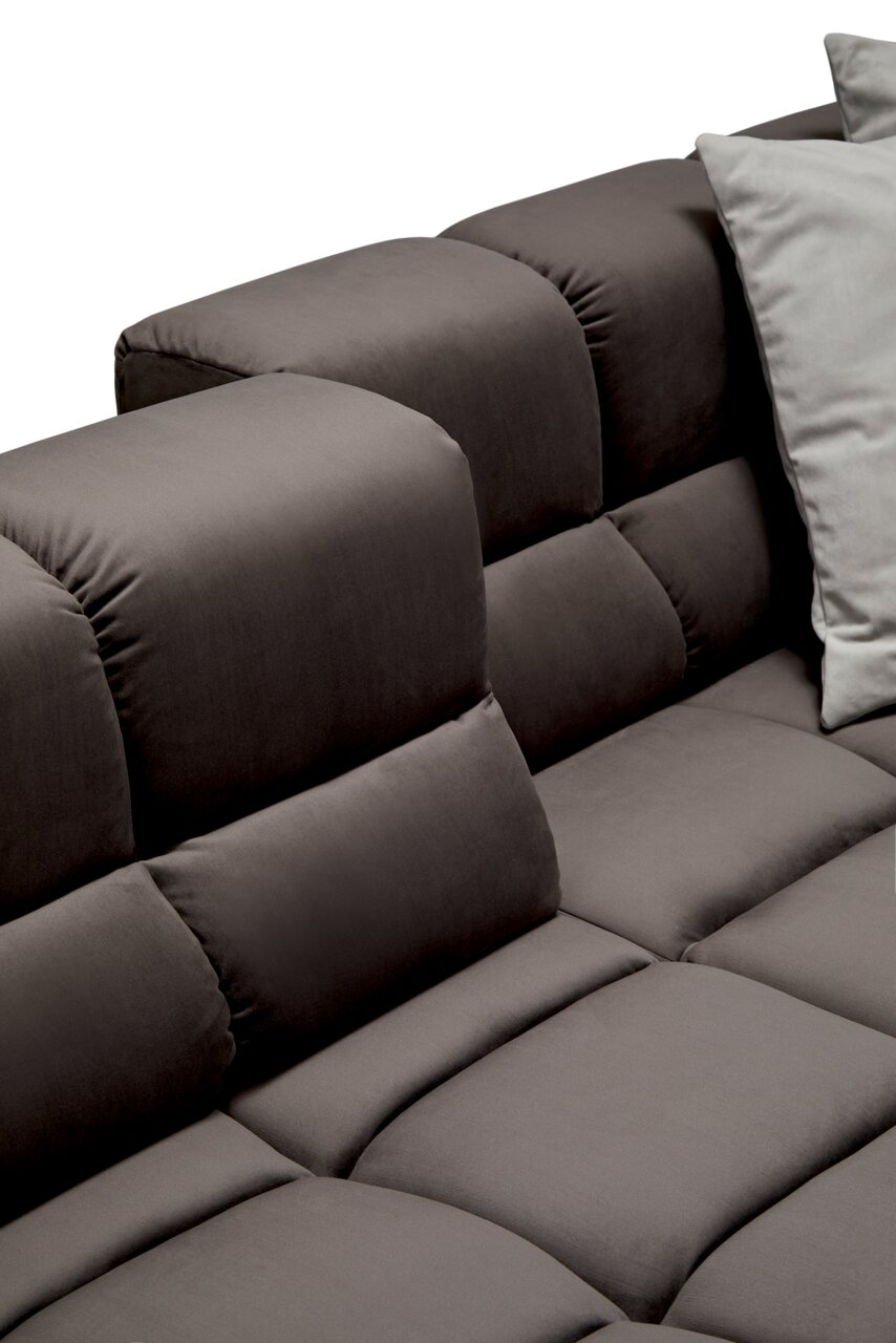 Close-up van een grijze longchair-set met zachte, gewatteerde kussens en een modern ontwerp, gezien vanaf de zijkant.