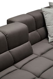 Nahaufnahme einer grauen Longchairkombination mit weichen, gepolsterten Kissen und einem modernen Design, seitliche Perspektive.