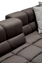 Close-up van een grijze longchair-set met zachte, gewatteerde kussens en een modern ontwerp, gezien vanaf de zijkant.