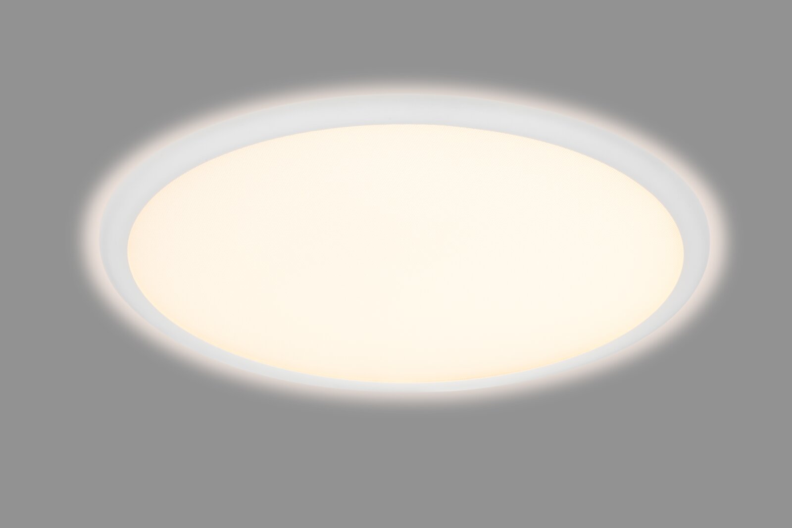 Ronde, platte led-plafondlamp met een wit frame en een warmwitte kap, in een licht schuin perspectief van onderaf tegen een grijze achtergrond