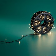 LED-Lichterkette auf einer Spule, seitliche Perspektive, leuchtend auf grünem Hintergrund