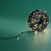 LED-Lichterkette auf einer Spule, seitliche Perspektive, leuchtend auf grünem Hintergrund