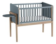 Babybett mit blauen Seitenwänden und einem kleinen, runden, an der Seite befestigten Tisch, seitliche Perspektive