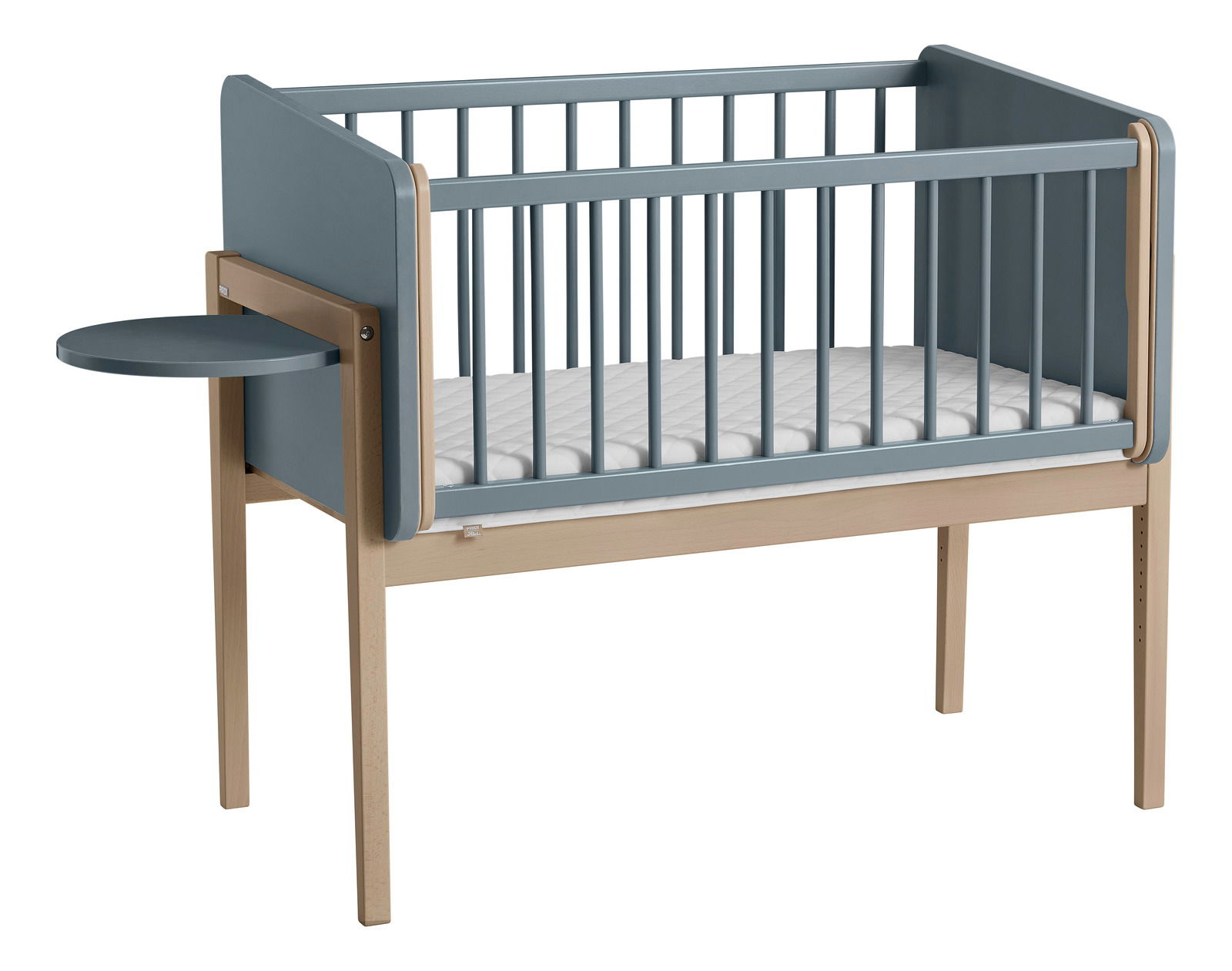 Babybett mit blauen Seitenwänden und einem kleinen, runden, an der Seite befestigten Tisch, seitliche Perspektive