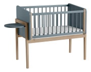 Babybett mit blauen Seitenwänden und einem kleinen, runden, an der Seite befestigten Tisch, seitliche Perspektive