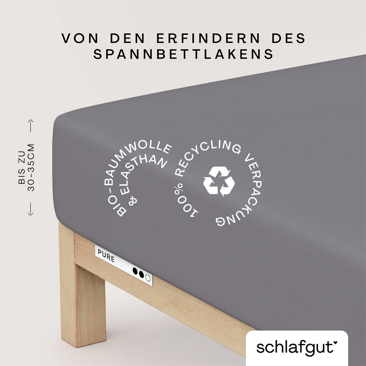 Spannbettlaken XL 128 in Grau, aus Bio-Baumwolle und Elasthan, auf einem Bettgestell. Perspektive von der Seite, zeigt die Höhe von 30-35 cm und das Recycling-Symbol.