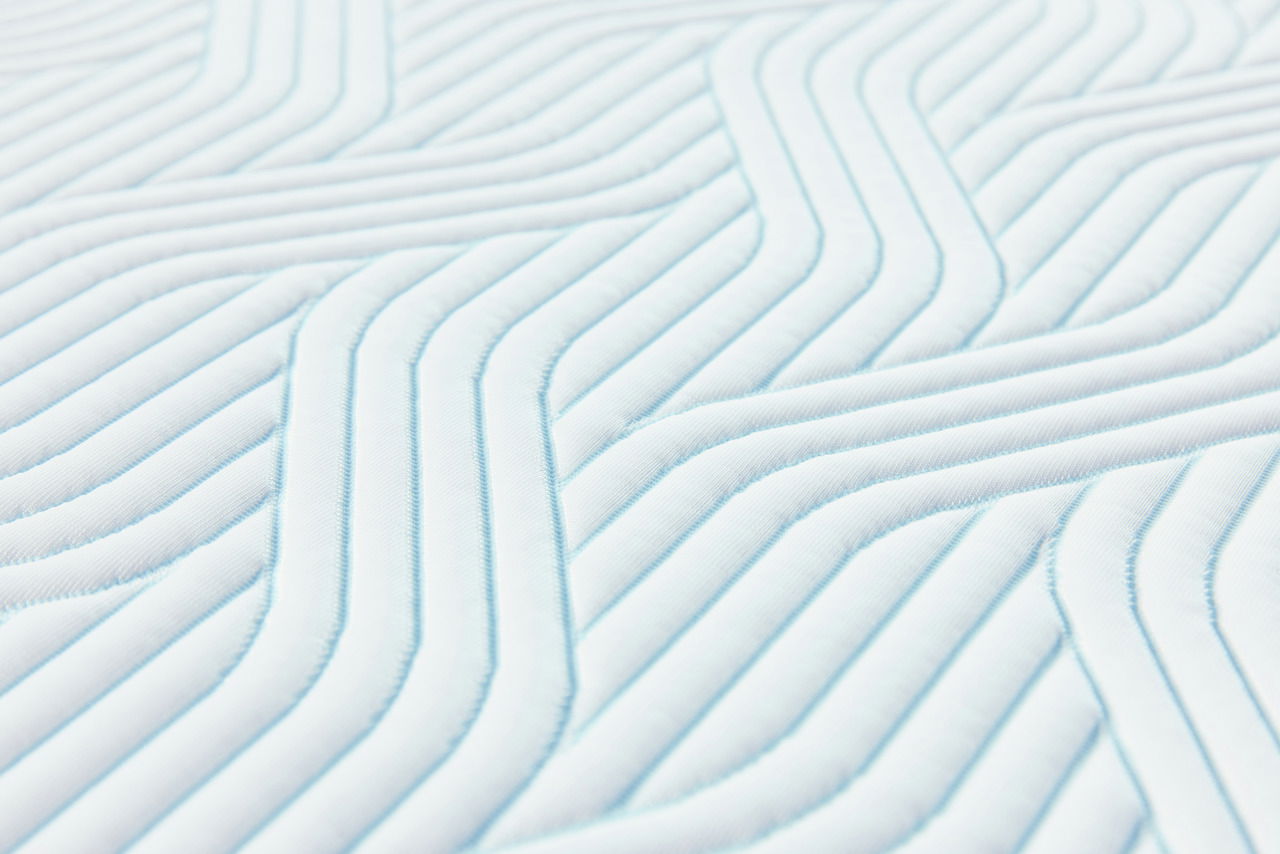 Tempur Topper Soft PRO PLUS SMARTCOOL Nahaufnahme eines gesteppten Matratzentoppers mit weichem, wellenförmigem Muster in Weiß und Hellblau.
