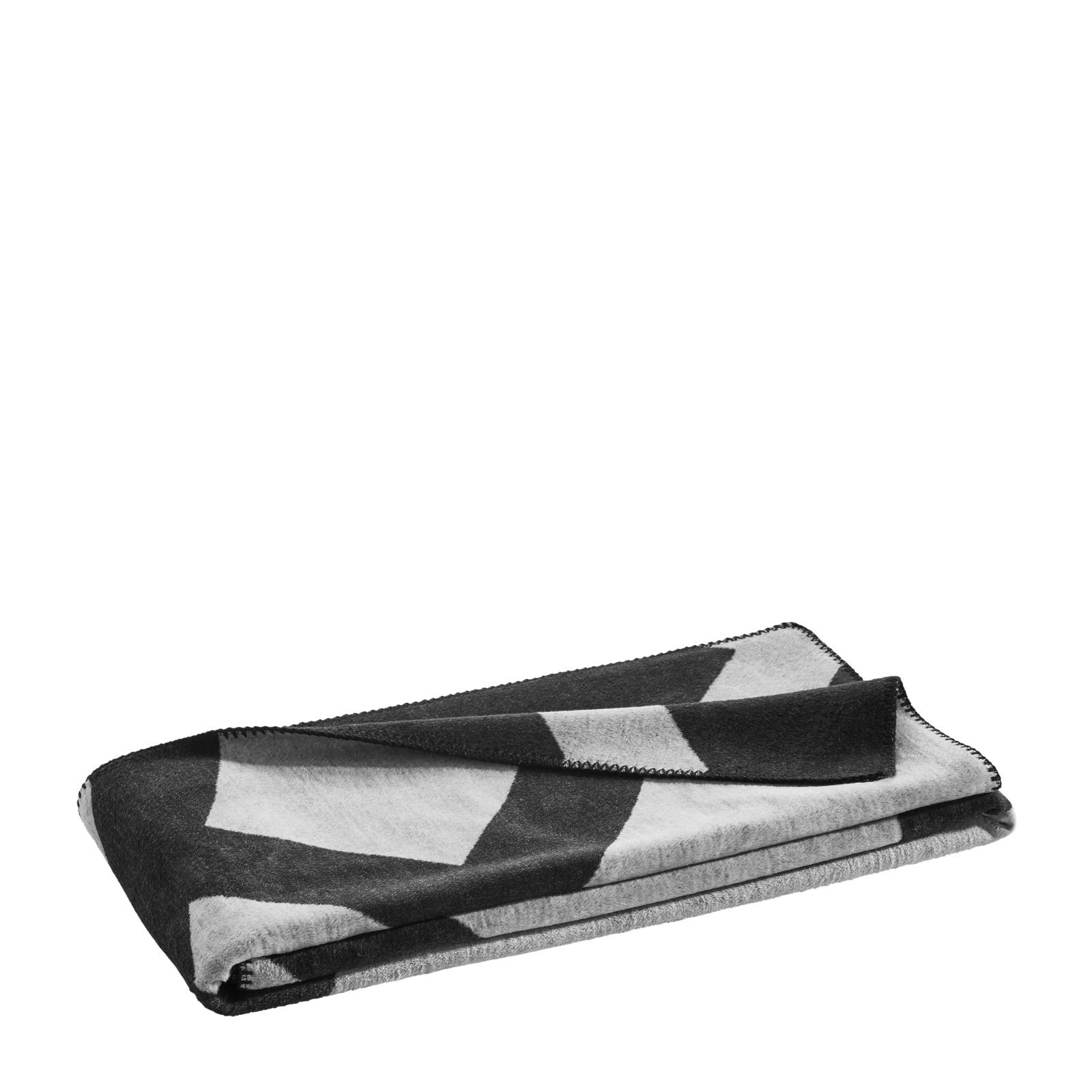 Gefaltete Wohndecke mit geometrischem Muster in Schwarz und Weiß, seitliche Perspektive