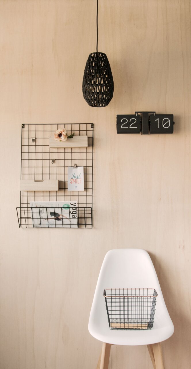 Wandklok Flip No Case in een modern interieur, aan de voorkant bevestigd aan een houten wand, naast een opbergrek van gaas en een hanglamp.
