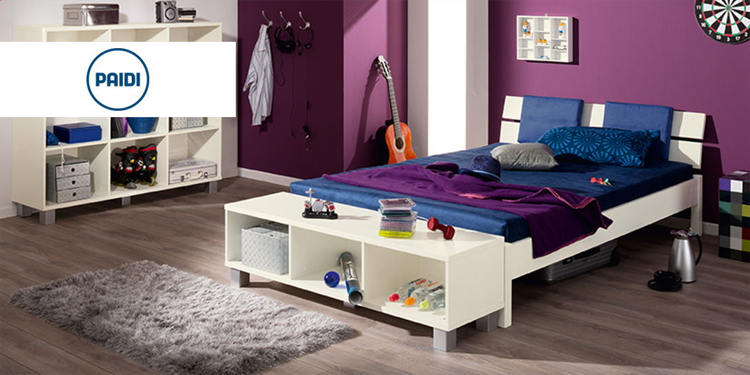 Modernes Jugendzimmer mit Bett, Regal, Teppich und Deko vor einer lila Wand.