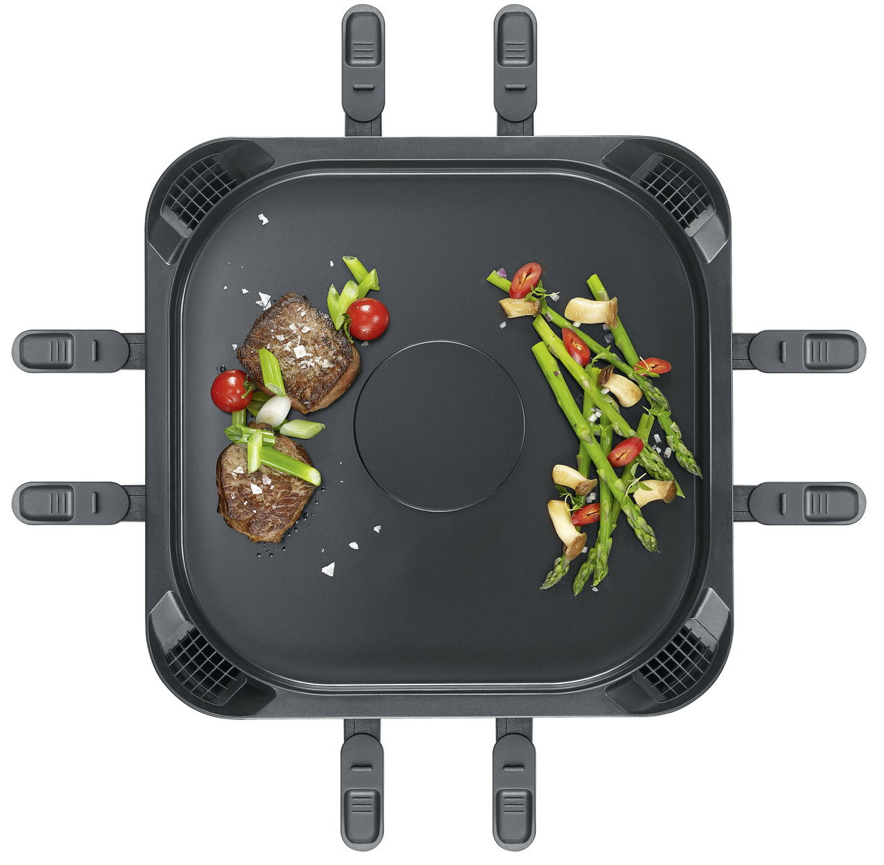 Draufsicht auf eine rauchfreie Raclette-Grillplatte mit Gemüse und Fleisch.