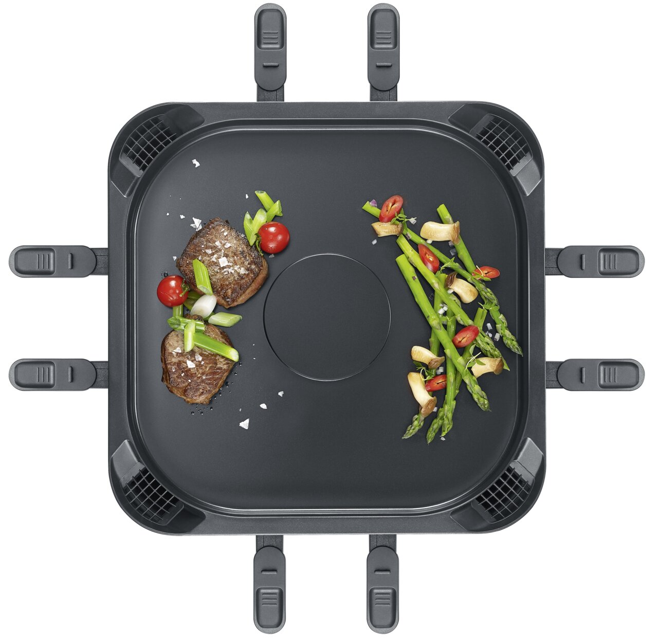 Draufsicht auf eine rauchfreie Raclette-Grillplatte mit Gemüse und Fleisch.