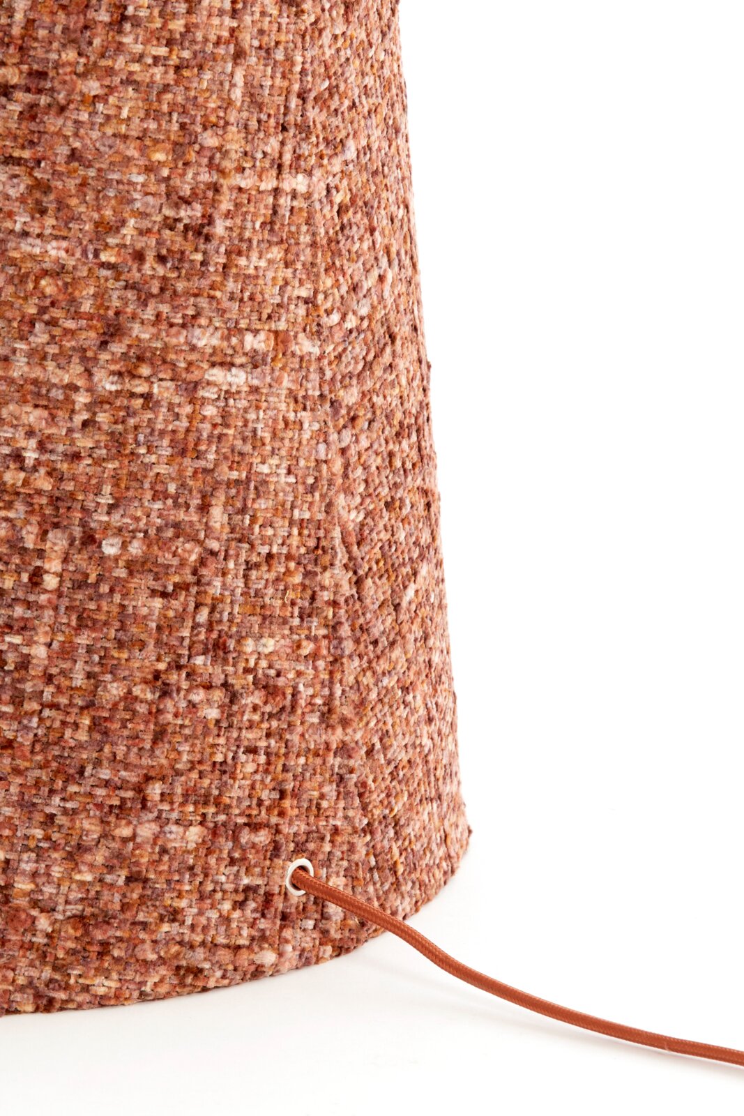 Detailopname vanuit zijaanzicht van een cilindervormige lamp met warm roestkleurig bouclétextiel en een bijpassend bruin snoer.