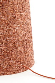 Detailopname vanuit zijaanzicht van een cilindervormige lamp met warm roestkleurig bouclétextiel en een bijpassend bruin snoer.