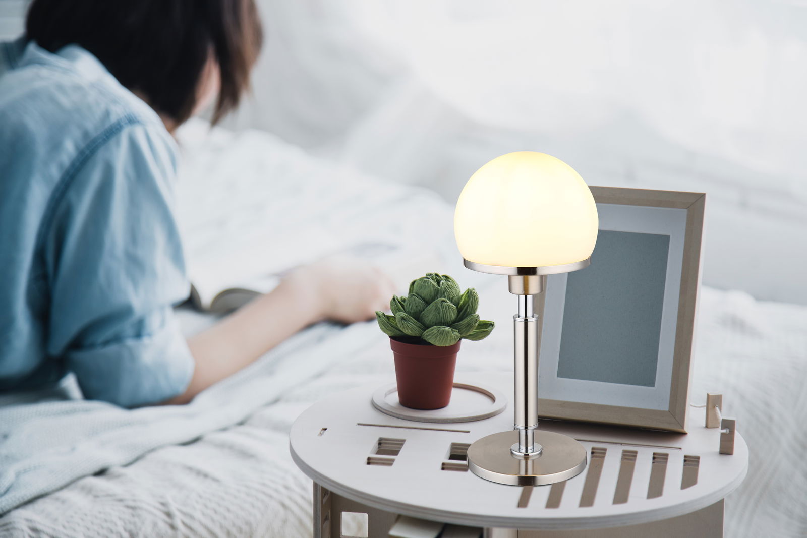 Tischleuchte HAKU von Globo Lighting auf einem runden Tisch neben einer Pflanze und einem Bilderrahmen, seitliche Perspektive