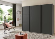Dreitüriger Schwebetürenschrank in dunklem Design, frontal fotografiert in einem modernen Wohnzimmer mit großen Fenstern und stilvoller Dekoration.