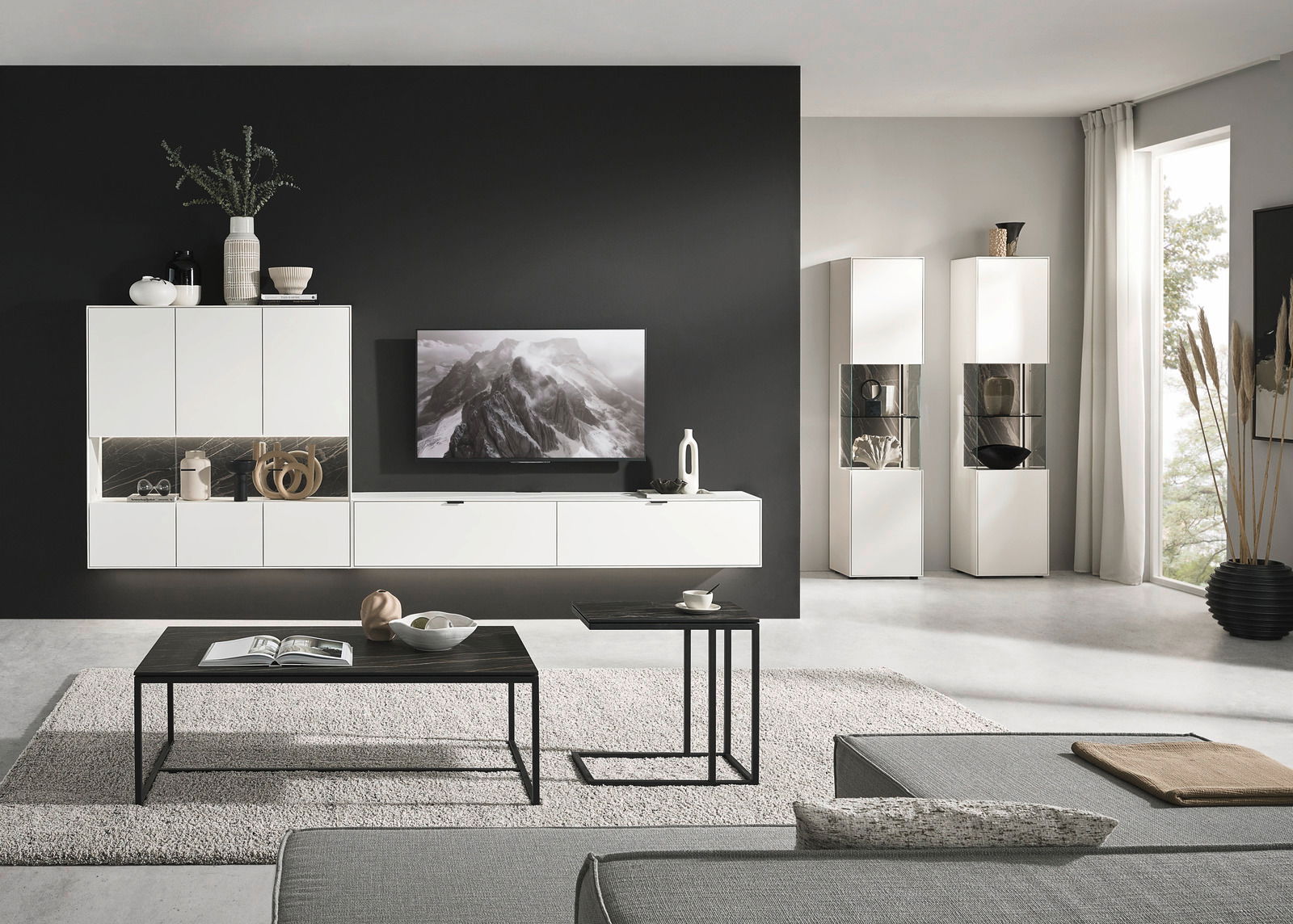 Dieter Knoll Wandcombinatie MONTESA Moderne Wohnzimmerwandkombination in Weiß mit schwarzen Akzenten, bestehend aus Hängeschränken, einem TV-Board und Vitrinen. Perspektive: Frontalansicht.