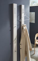 Zwei moderne Garderobenpaneele in Beige an einer dunkelgrauen Wand, mit Haken und einem beigen Mantel, aus seitlicher Perspektive fotografiert.