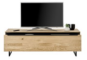 Klein houten tv-meubel met een zwart metalen onderstel, met daarop een flatscreen-tv, een afstandsbediening en decoratie. Vooraanzicht.