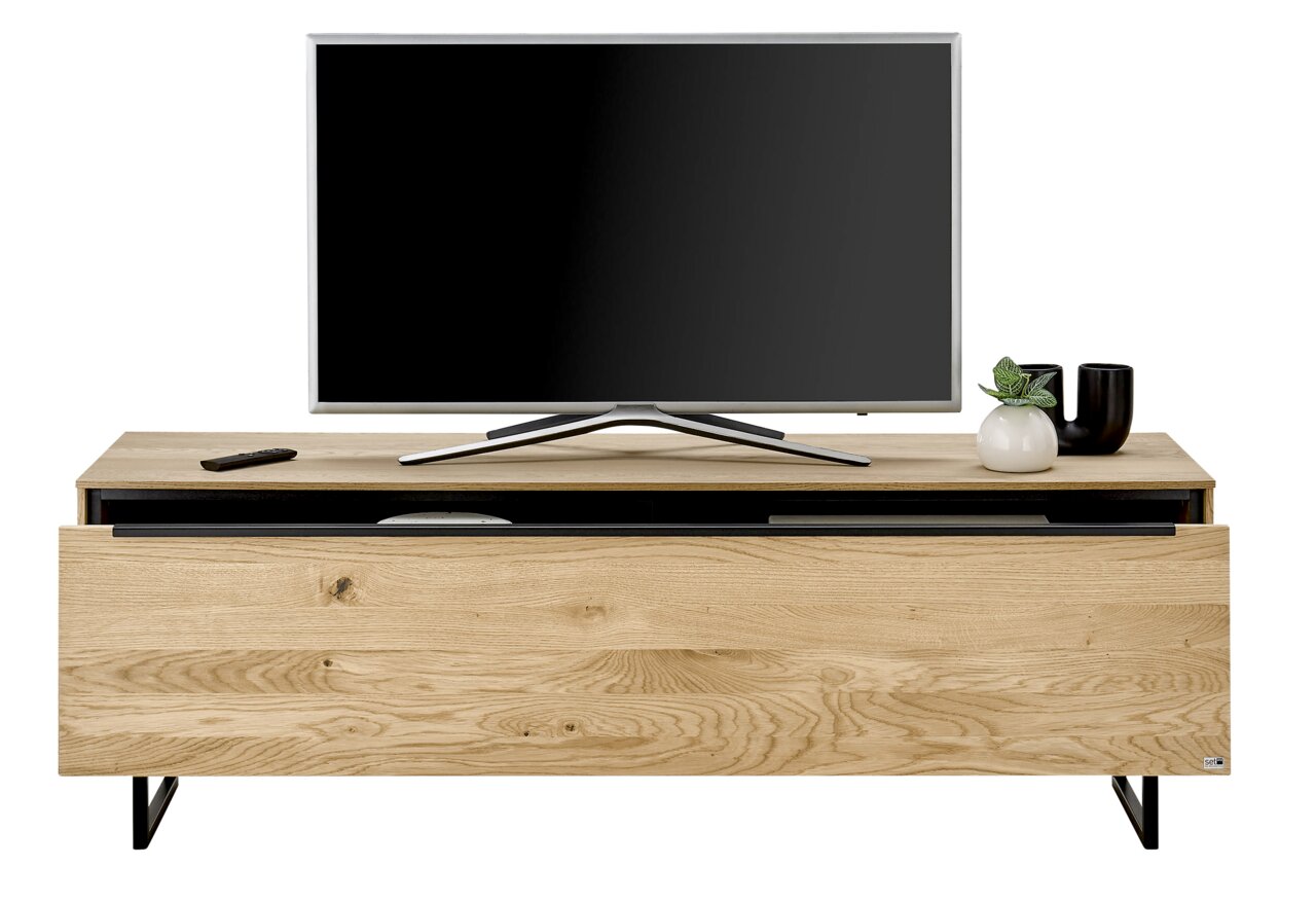 Klein houten tv-meubel met een zwart metalen onderstel, met daarop een flatscreen-tv, een afstandsbediening en decoratie. Vooraanzicht.