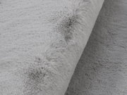 Nahaufnahme eines grauen Fellteppichs mit weicher Textur, seitliche Perspektive