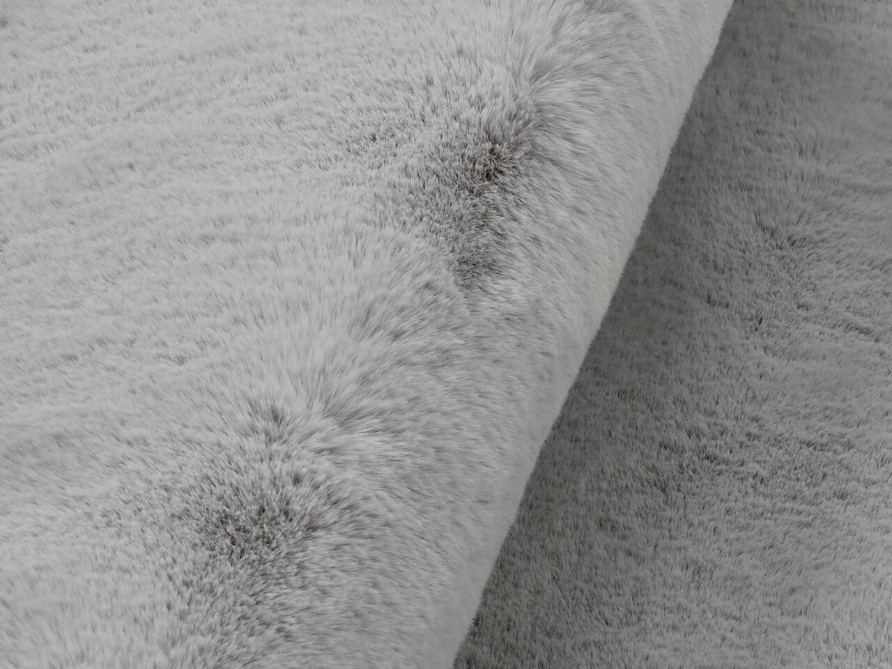Nahaufnahme eines grauen Fellteppichs mit weicher Textur, seitliche Perspektive