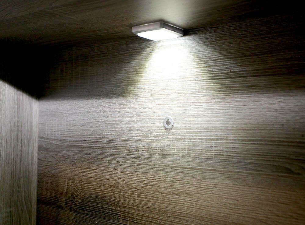 Unterbaubeleuchtung mit einem Lichtpunkt, von unten betrachtet, montiert an einer Holzoberfläche.