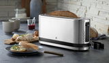 Silberner Langschlitz-Toaster in einer modernen Küche, seitliche Perspektive, mit einer Scheibe Brot im Toaster.