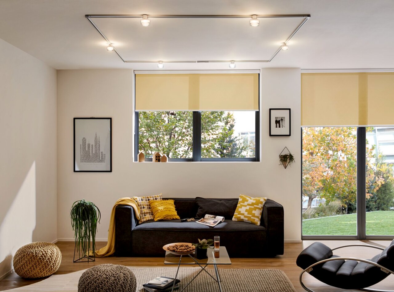 Moderne Wohnzimmerbeleuchtung mit Schienensystem und mehreren Spots an der Decke, Perspektive von vorne.