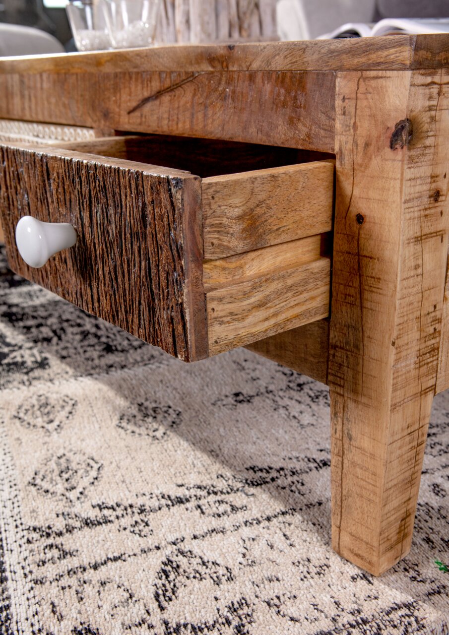 Nahaufnahme eines rustikalen Couchtisches mit geöffneter Schublade aus Holz, seitliche Perspektive