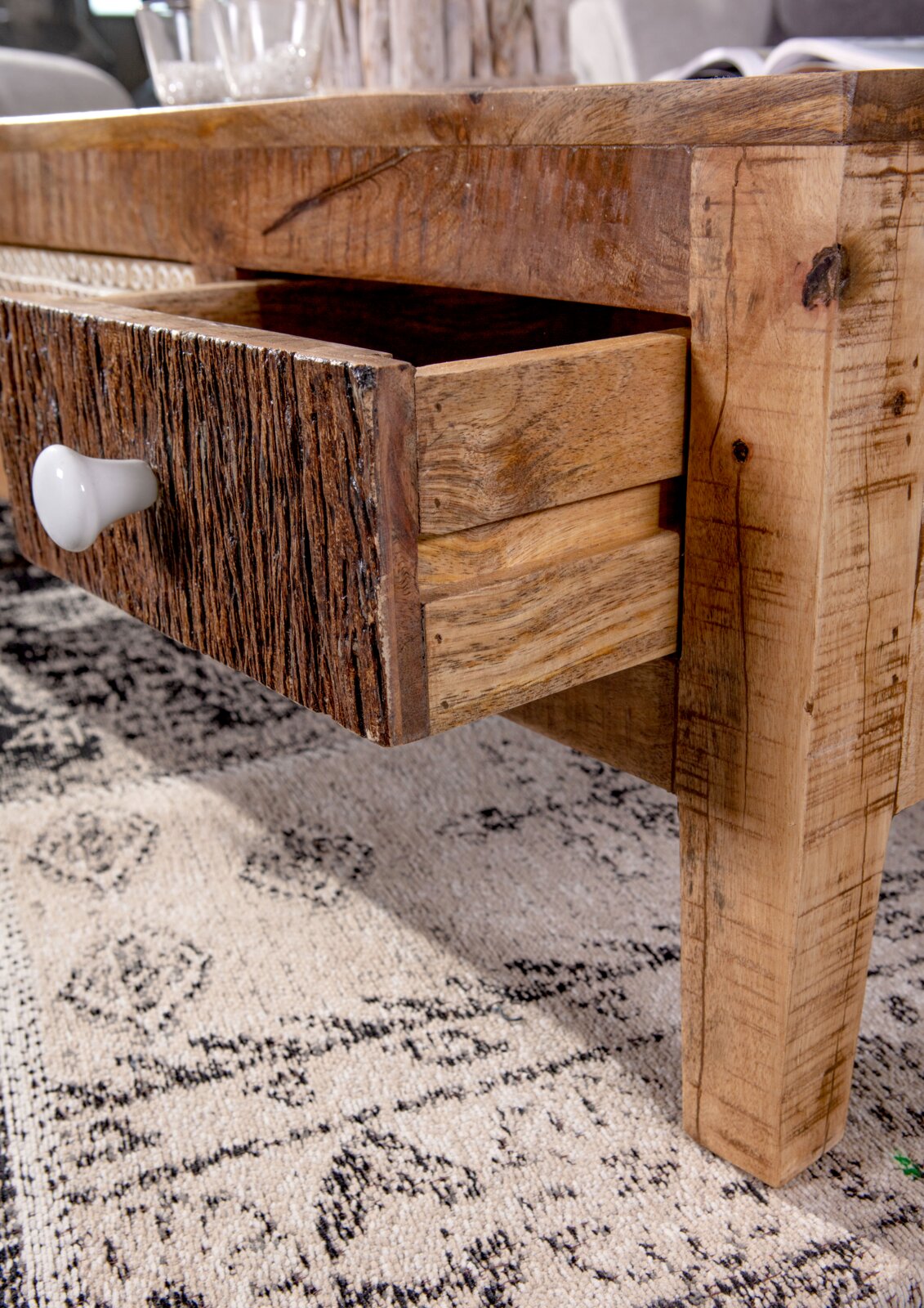 Nahaufnahme eines rustikalen Couchtisches mit geöffneter Schublade aus Holz, seitliche Perspektive