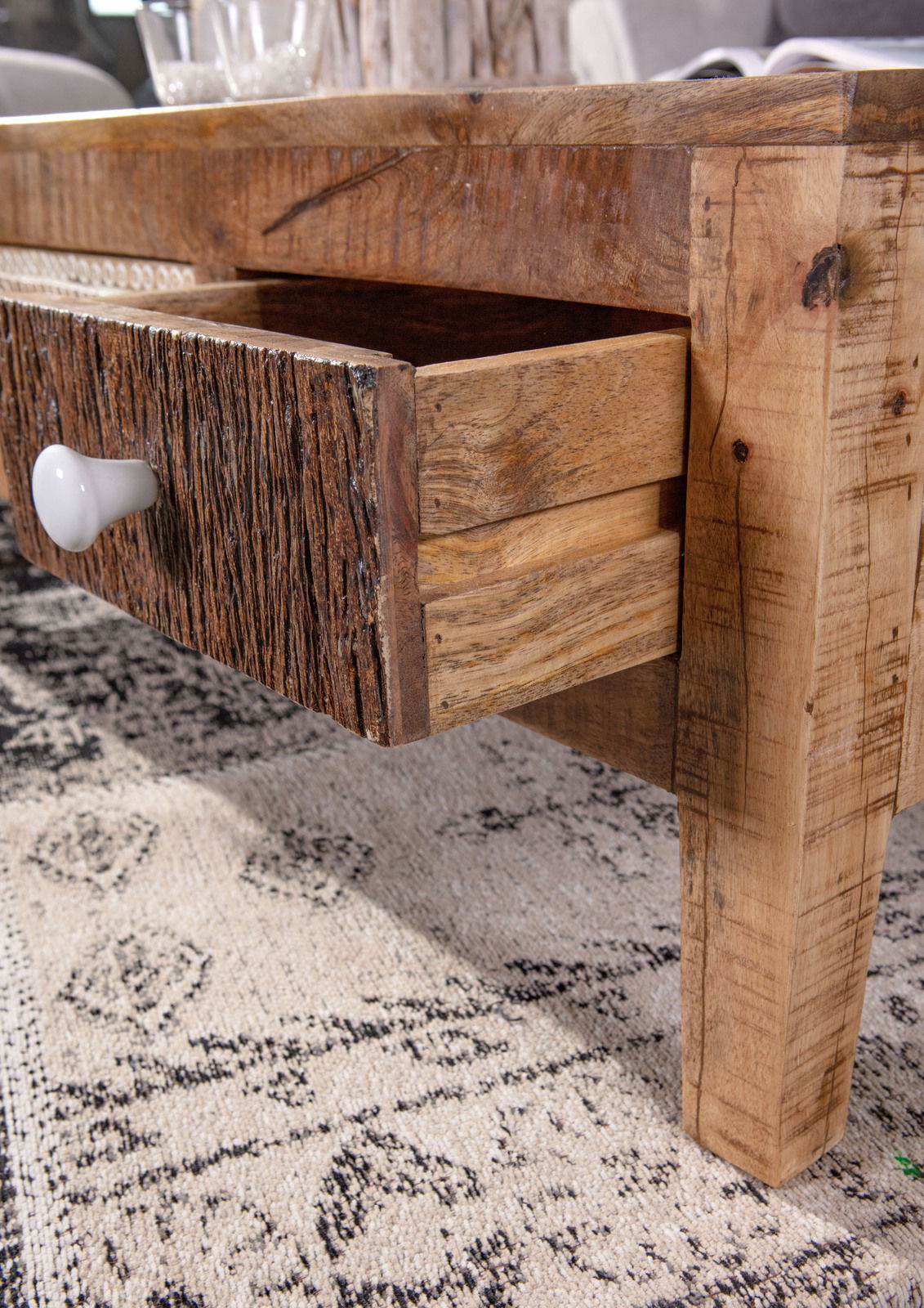 Nahaufnahme eines rustikalen Couchtisches mit geöffneter Schublade aus Holz, seitliche Perspektive