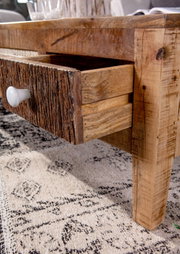 Close-up van een rustieke houten salontafel met geopende lade, gezien vanaf de zijkant