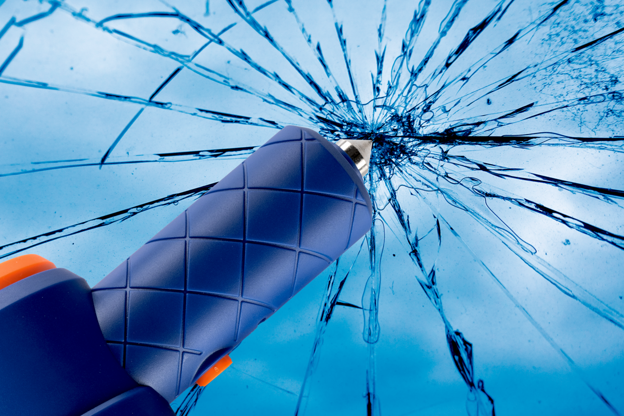 Nahaufnahme eines blauen Werkzeugs mit rutschfestem Griff, das auf eine zerbrochene Glasoberfläche zeigt.
