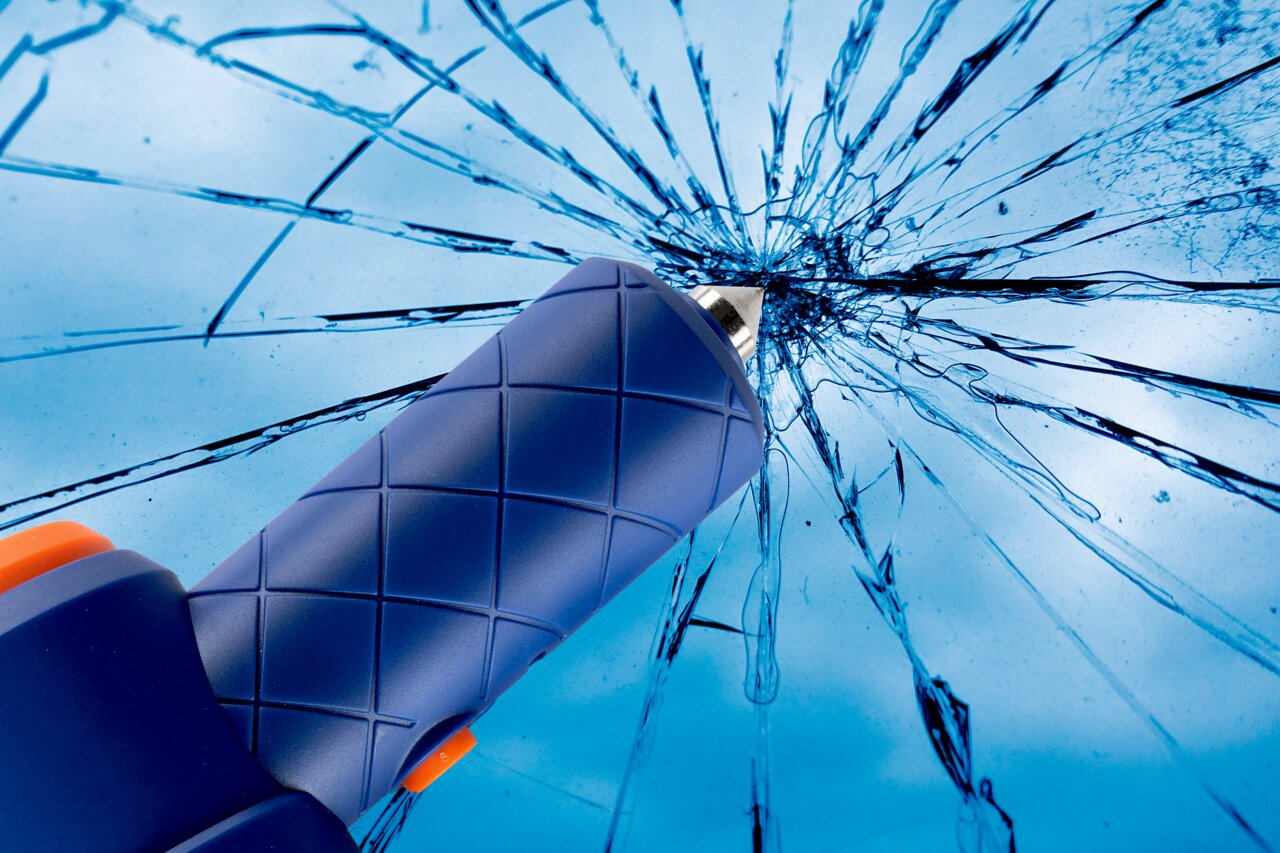 Nahaufnahme eines blauen Werkzeugs mit rutschfestem Griff, das auf eine zerbrochene Glasoberfläche zeigt.