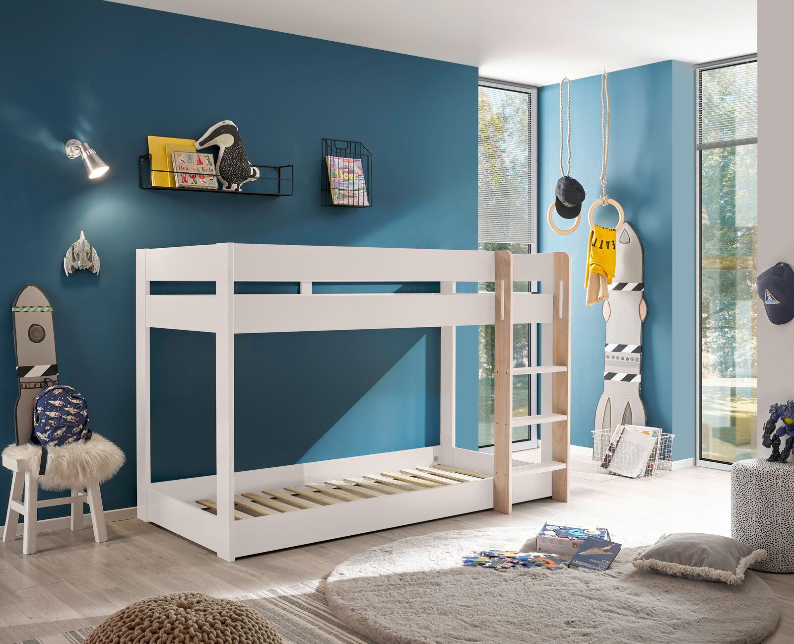 Weißes Etagenbett in einem modernen Kinderzimmer mit blauer Wand, von der Seite betrachtet.
