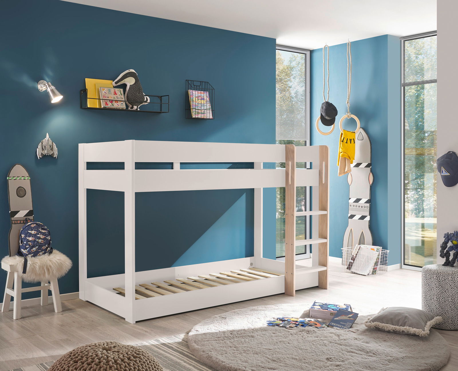 Weißes Etagenbett in einem modernen Kinderzimmer mit blauer Wand, von der Seite betrachtet.