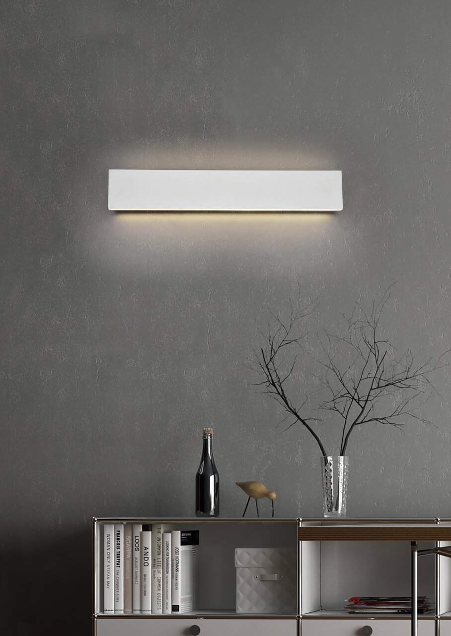 Moderne Wandleuchte Concha in rechteckiger Form, frontal an einer grauen Wand montiert, mit sanftem Lichtschein nach oben und unten.