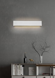 Moderne wandlamp Concha in rechthoekige vorm, aan de voorkant gemonteerd op een grijze muur, met een zacht licht dat zowel naar boven als naar beneden schijnt.