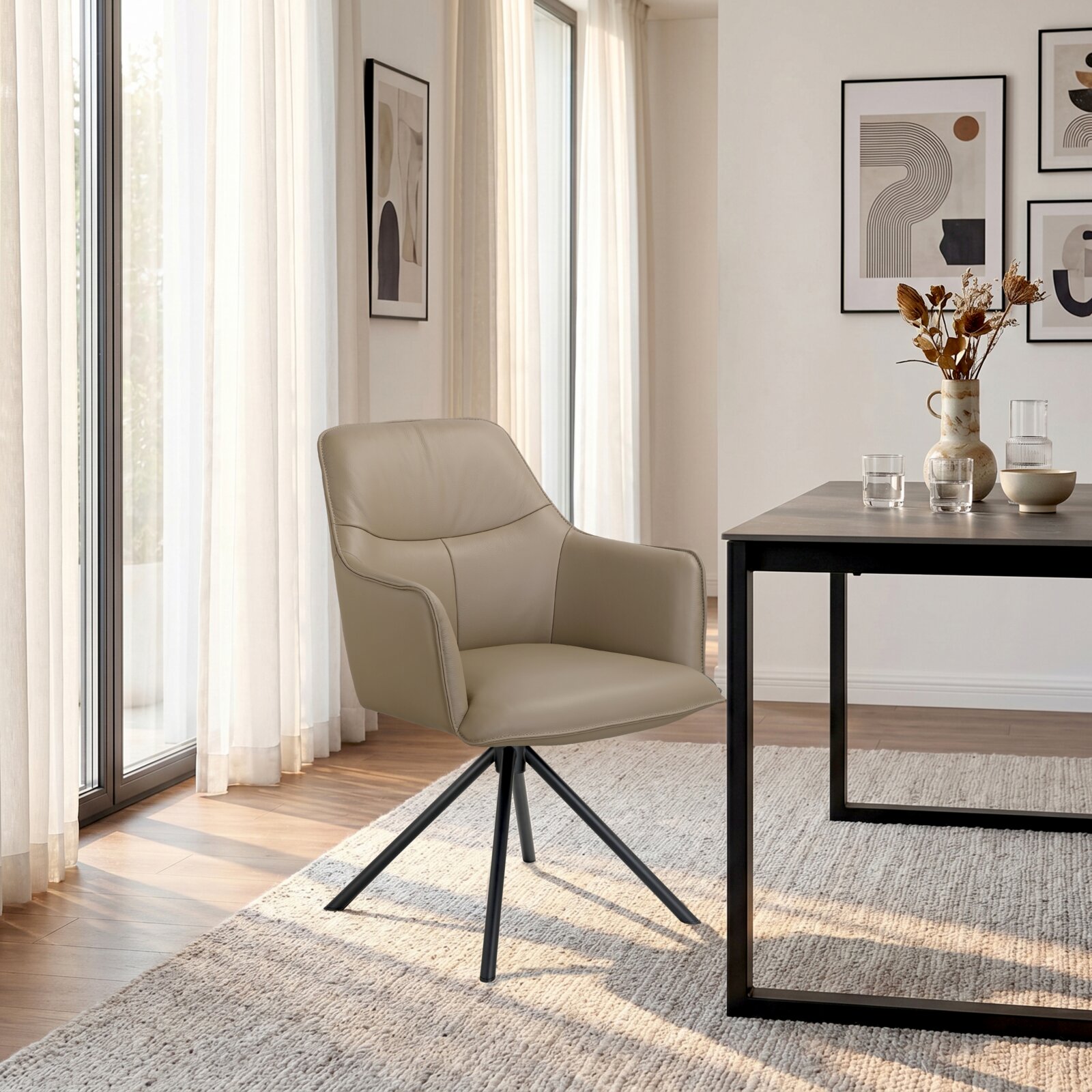 Beige gestoffeerde eetkamerstoel met armleuningen en zwart metalen onderstel, schuin van voren gezien in een modern, licht interieur