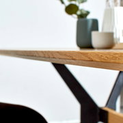 Nahaufnahme eines Esstisches mit Holzplatte und Metallgestell, seitliche Perspektive