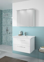 Moderner weißer Badblock mit zwei Schubladen und Waschbecken, frontal fotografiert, vor einer türkisfarbenen Wand mit Duschbereich.