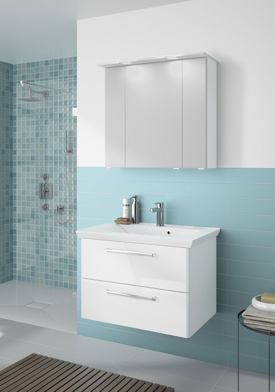 Moderner weißer Badblock mit zwei Schubladen und Waschbecken, frontal fotografiert, vor einer türkisfarbenen Wand mit Duschbereich.