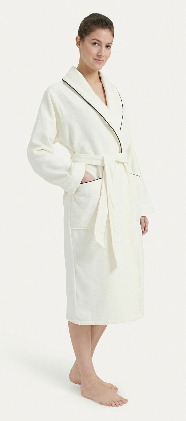 Frau in einem weißen Bademantel mit Schalkragen und schwarzer Paspelierung, von vorne betrachtet.