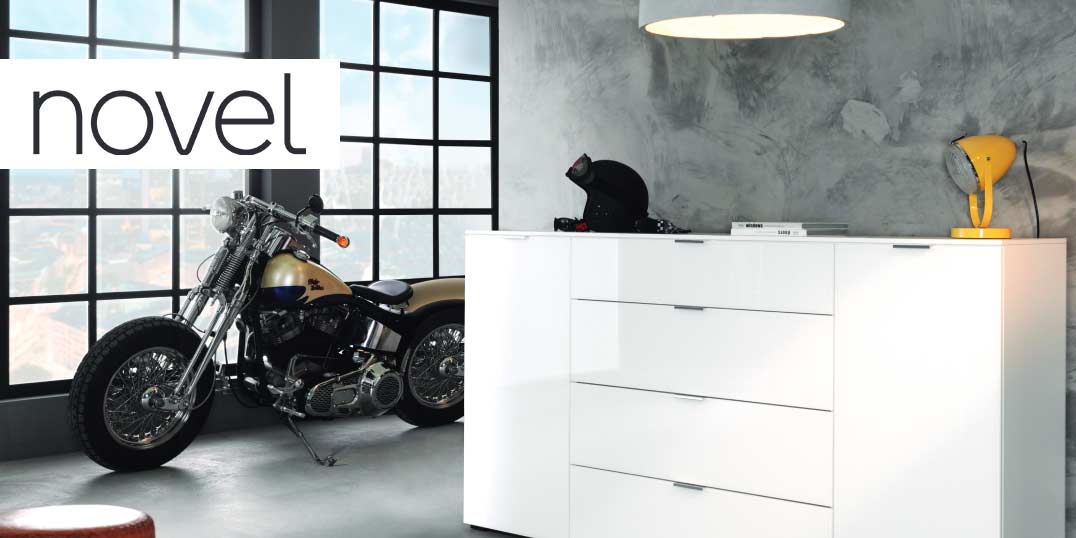 Interieur mit einer weißen Kommode der Marke Novel, einem Motorrad und Wanddekor im Industriestil.